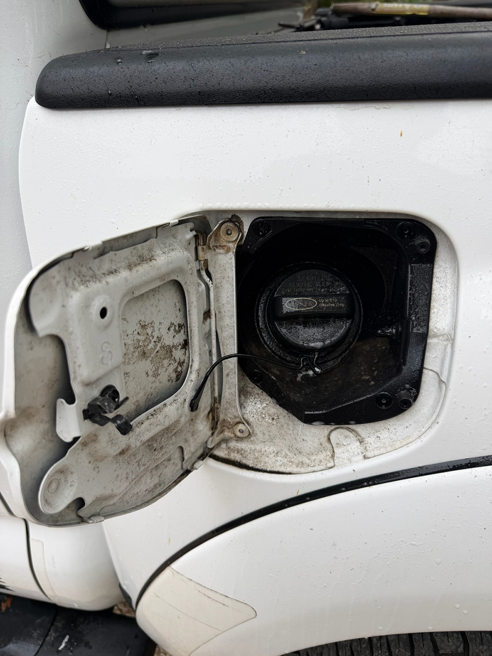 A dirty fuel door before a professional detailing pass, the kind of embedded grime a home wash typically misses