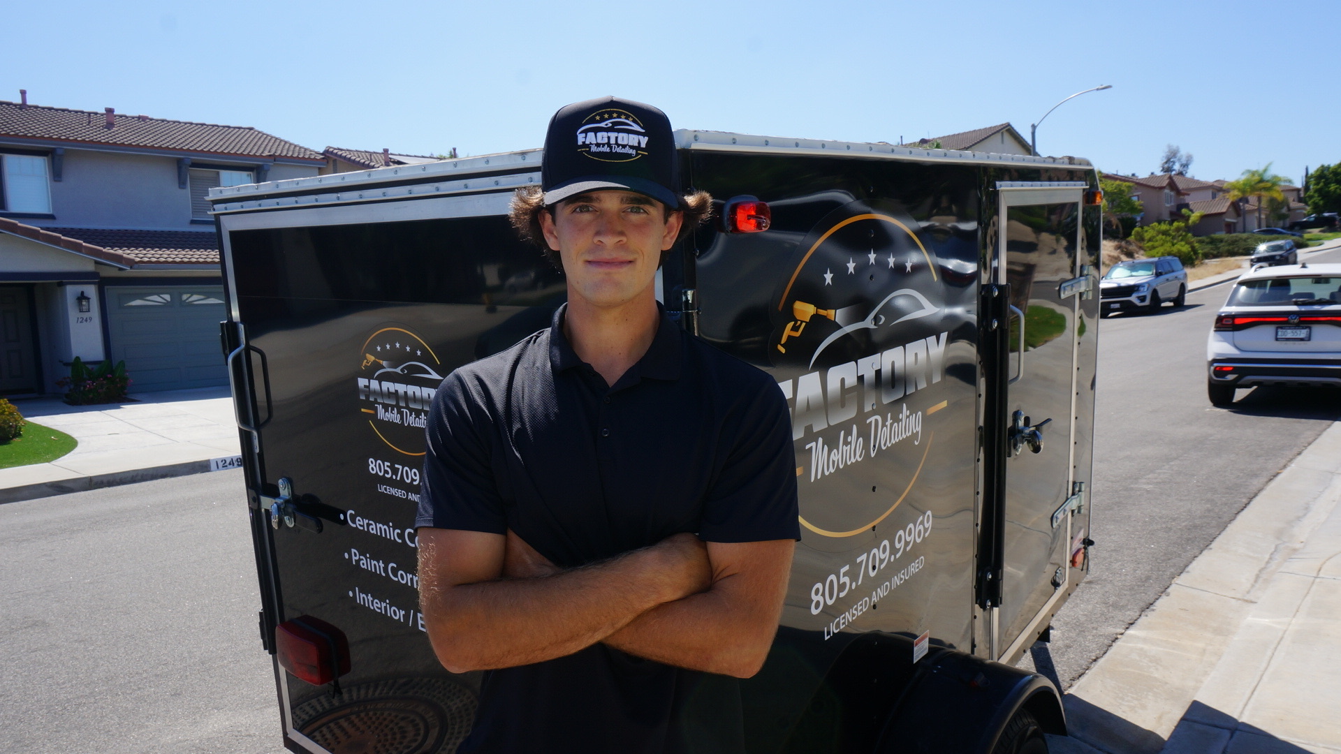 Mobile detailing technician working from the branded trailer at a residential driveway