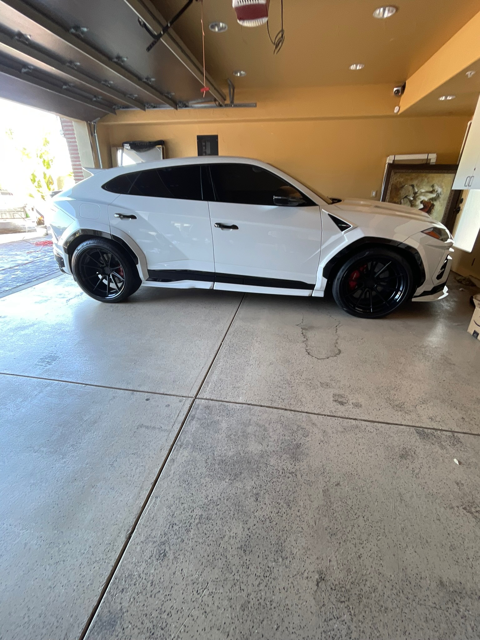 White Lamborghini Urus after a ceramic coating application in a residential garage